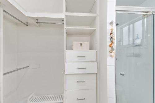 a walk in closet with white drawers and a shower at Keiraville Poolside Escape - University Proximity in Keiraville