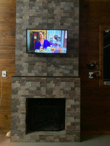 a tv on top of a stone fireplace at Pousada Vale do Tigre in Rio Rufino