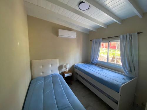 een slaapkamer met een blauw bed en een raam bij BOSQUE LIBERTAD Casa PB in Mar Azul