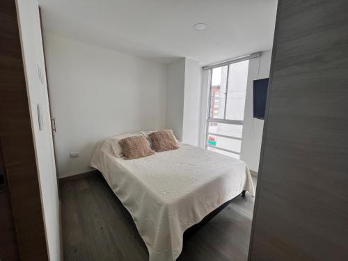 a small white bedroom with a bed and a window at Urban Manizales 703 in Manizales