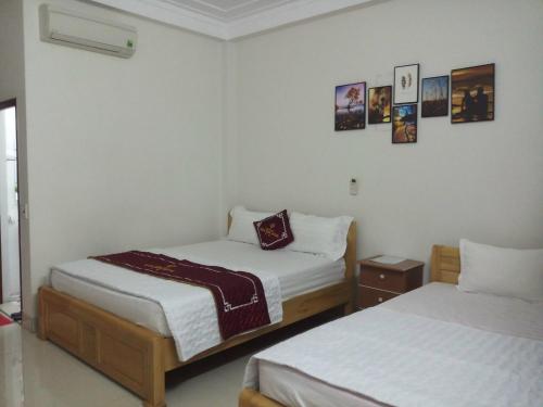 two beds in a room with white walls at hằng hiên hotel in Lục Ngạn