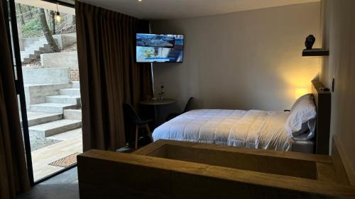 a bedroom with a bed and a tv on the wall at Roots Luxury Cabins in Mineral del Monte