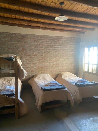 a bedroom with two bunk beds and a brick wall at EL TOPON cabañas in Albardón