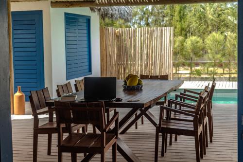 a wooden table with chairs and a laptop on a deck at Casa Pipa - Pontal de Maceió in Fortim