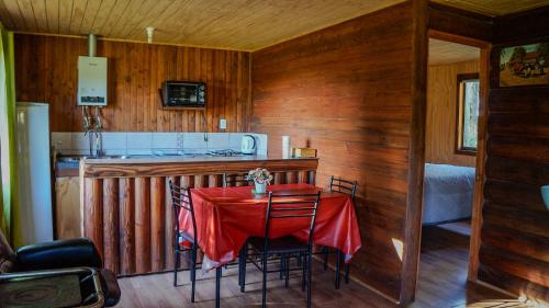 a kitchen with a table with a red table cloth at Cabañas Cerro Colorado Lago Colbún in Talca