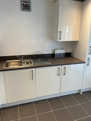 a kitchen with white cabinets and a sink at 28 croft holm 