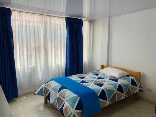 a bedroom with a bed and a window with blue curtains at Hostel Bogotá Kings in Bogotá