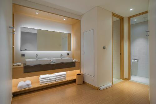 uma casa de banho com 2 lavatórios e um espelho grande em Healing Stay KOSMOS em Ullŭng