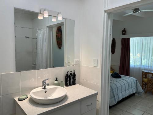 baño con lavabo, espejo y cama en Magnetic Island Resort Studio, en Nelly Bay