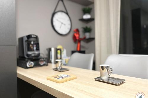 un comptoir avec deux tasses et une horloge au mur dans l'établissement Le Port Enchanté - Parking - Terrasse, à Caen