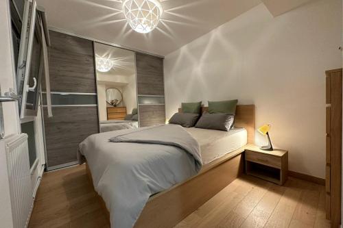 une chambre avec un grand lit et un lustre dans l'établissement Le Port Enchanté - Parking - Terrasse, à Caen