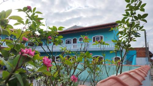 una casa azul y blanca con flores delante en Apartamento dos Sonhos en Ilha Comprida