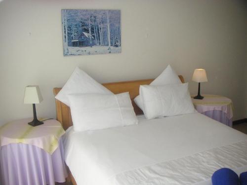 una camera da letto con un letto con cuscini bianchi e due tavoli di WatersideLiving MS11 a Jeffreys Bay
