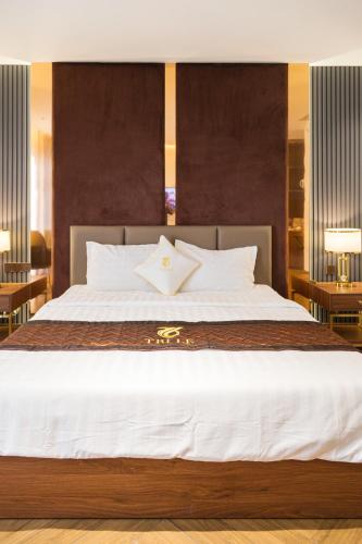 a bedroom with a large white bed with two tables at Hotel Trí Lê PREMIER in Cao Lãnh