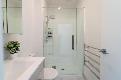 baño blanco con ducha y lavamanos en Harbour Haven - A Sunset Oasis! en Tauranga