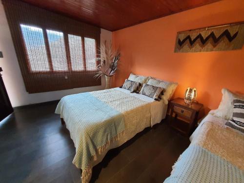 a bedroom with two beds and an orange wall at Hospedaje rural - Finca la Aurora - Caqueza in Cáqueza