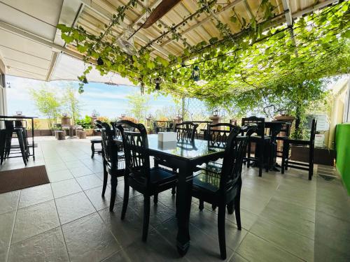 uma sala de jantar com mesa, cadeiras e plantas em Pontian Garden Hotel em Pontian Kechil