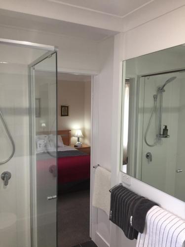 baño con ducha, espejo y cama en Wanderers Retreat, en Jindabyne