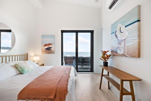 a bedroom with a bed and a table and a window at Beachfront Luxury Suite #19 at THE BEACH HOUSE in Campbell River