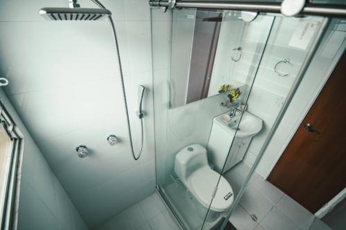 La salle de bains est pourvue de toilettes et d'une douche en verre. dans l'établissement Lindo Apartamento - Central, à Manizales