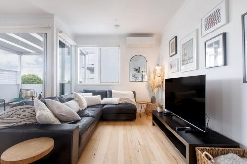a living room with a black couch and a tv at 'Laidback Lygon' A Two-storey Inner-city Oasis in Melbourne