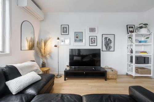 a living room with a black couch and a tv at 'Laidback Lygon' A Two-storey Inner-city Oasis in Melbourne