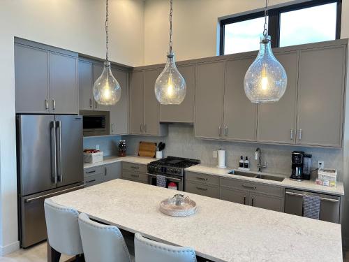 a kitchen with a large island with chairs and lights at Beachfront Villa #14 at The Beach House in Campbell River