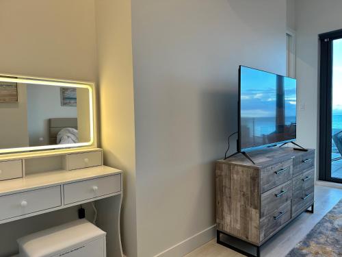 a bathroom with a dresser with a mirror and a tv at Saratoga Serenity at THE BEACH HOUSE in Campbell River