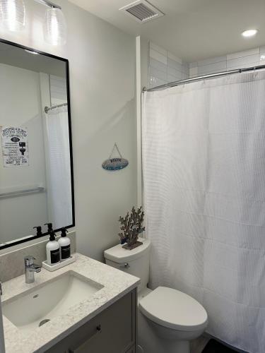 a white bathroom with a toilet and a sink at Beachfront Villa #14 at The Beach House in Campbell River