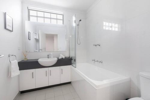 a white bathroom with a sink and a shower at 'Laidback Lygon' A Two-storey Inner-city Oasis in Melbourne