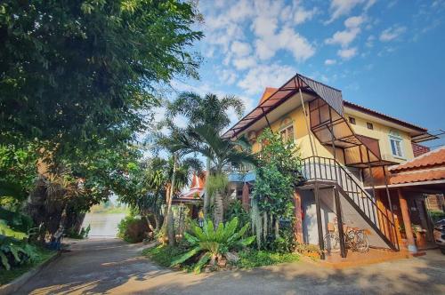 Maison jaune avec balcon et palmiers dans l'établissement Ruen Thai Ban Rim Nam, à Kamphaeng Phet