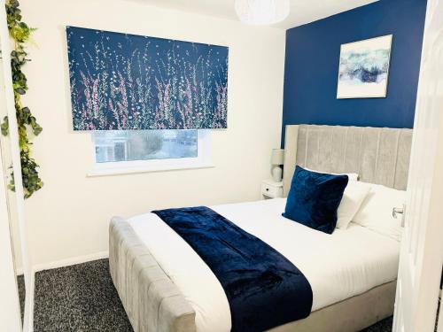 a bedroom with a bed with a blue accent wall at 2BR*Free Parking*Off A12*Family*Contractors in Barkingside