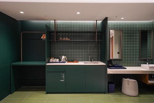 a kitchen with green tiled walls and a sink at Hotel Ground27 in Busan