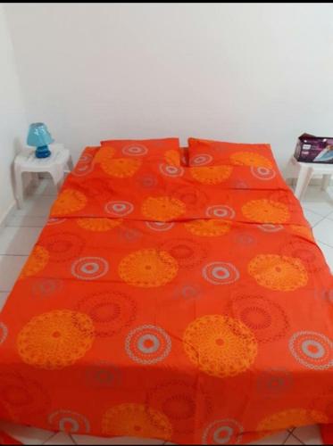 - un couvre-lit orange avec des fleurs blanches et orange dans l'établissement F2 pointe-à-pitre proche terminal de croisière, à Pointe-à-Pitre