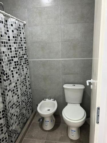 a bathroom with a toilet and a shower curtain at Departamento tornquist por día in Tornquist