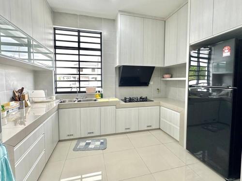 uma grande cozinha com armários brancos e uma televisão em Mojisu Homestay 麻吉宿 em Miri