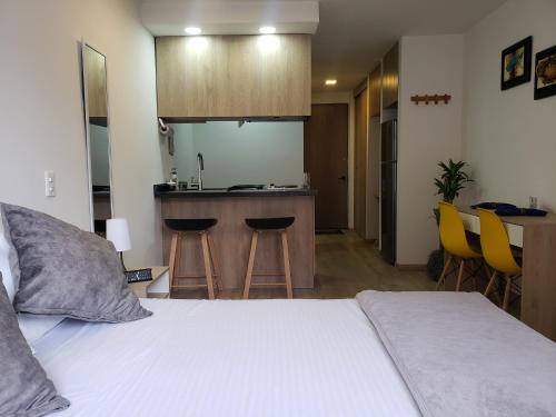 een slaapkamer met een bed en een keuken met gele stoelen bij Chapinero Central in Bogota