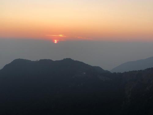 a sunset over a mountain range with the sun in the sky at Free style camps in Mussoorie