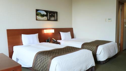 a hotel room with two beds with white sheets at Chion-in Wajun Kaikan in Kyoto
