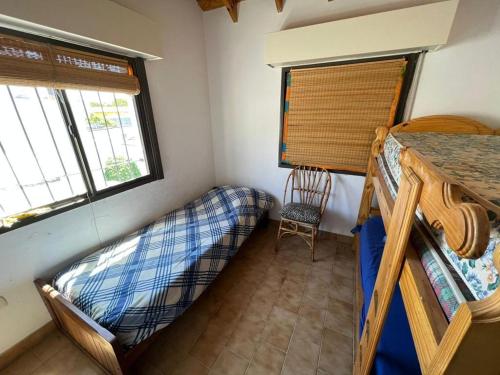 a bedroom with a bunk bed and a chair in a room at Casa en el Balneario El Cóndor, muy cerquita del mar. in Viedma