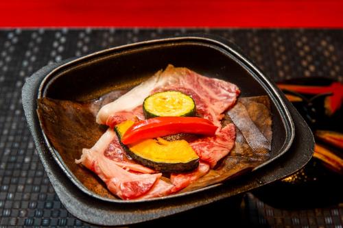 a pan filled with meat and vegetables on a table at Mashikokan Satoyama Resort Hotel in Mashiko