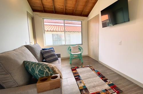 a living room with a couch and a television at Casa Campestre en zona exclusiva con Jacuzzi, a 10 min del aeropuerto, 20 min parque del café, WiFi, parqueadero privado, vigilancia 24 hrs y amplias zonas sociales in Armenia
