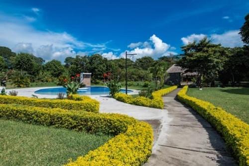 a walkway in a park with yellow flowers at Hotel Victoria in Moyogalpa