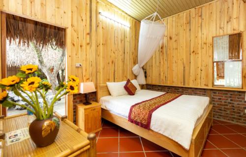 1 dormitorio con 1 cama y un jarrón de flores en Hoalu Ecolodge Homestay en Ninh Binh