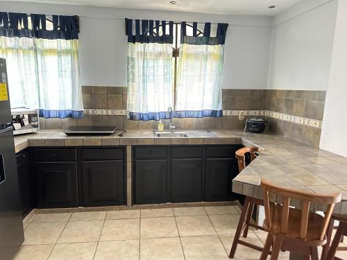 eine Küche mit schwarzen Schränken, einem Waschbecken und einem Tisch in der Unterkunft Hermosa casa para descanso in Linda Vista