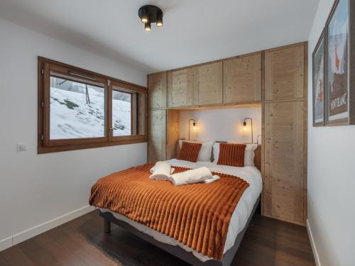 une chambre avec un grand lit avec une couverture orange dans l'établissement Appartement spacieux à Megève, 3 ch, près des pistes, parking privé - FR-1-569-139, à Megève