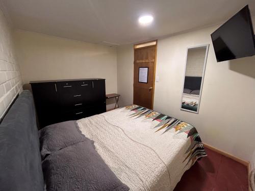 1 dormitorio con 1 cama y TV de pantalla plana en Chez Humbert en Santiago