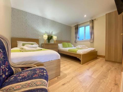 una habitación de hotel con 2 camas y una silla en Lake District cottage in 1 acre gardens off M6 en Penrith