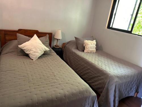 1 dormitorio con 2 camas y ventana en Casa Maqui, en Talca