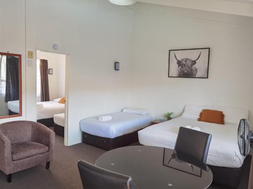Habitación de hotel con 2 camas, mesa y silla en Cortez Motel, en Whakatane